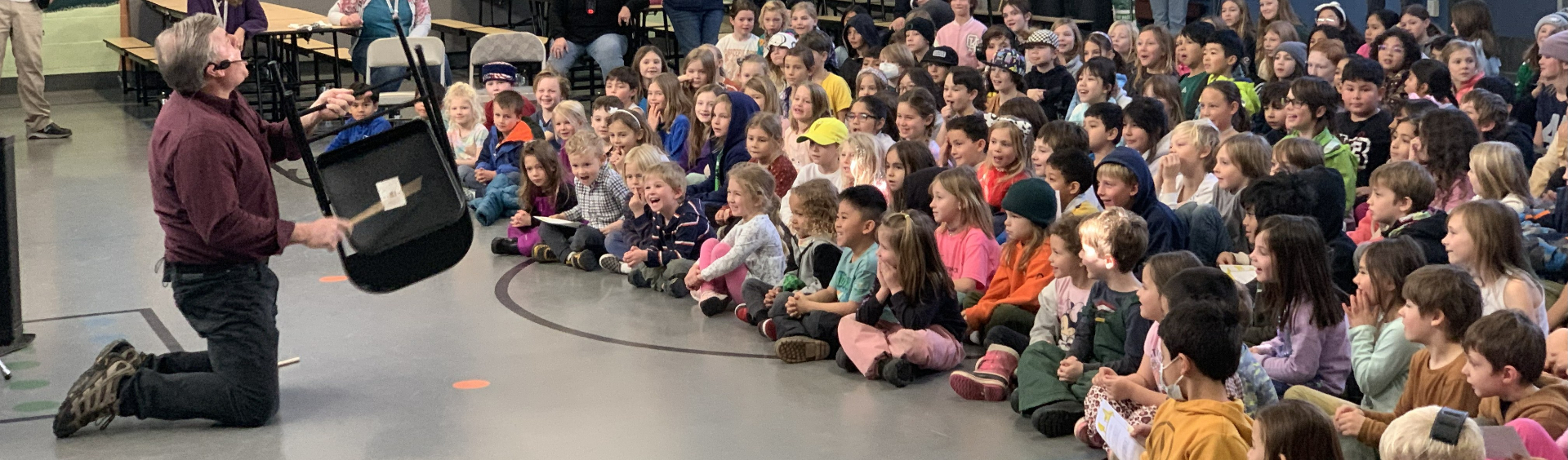TTSM instructors performing at a school assembly with hundreds of engaged students