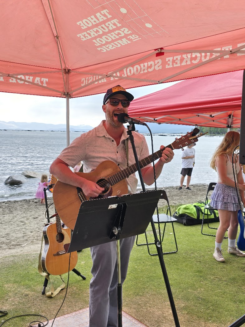 Guitarist performing under TTSM tent at lakeside event