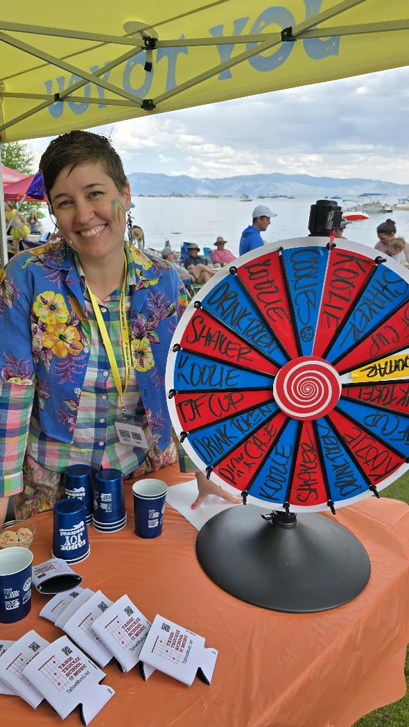 Volunteer at TTSM booth with prize wheel at Tahoe Joy Festival
