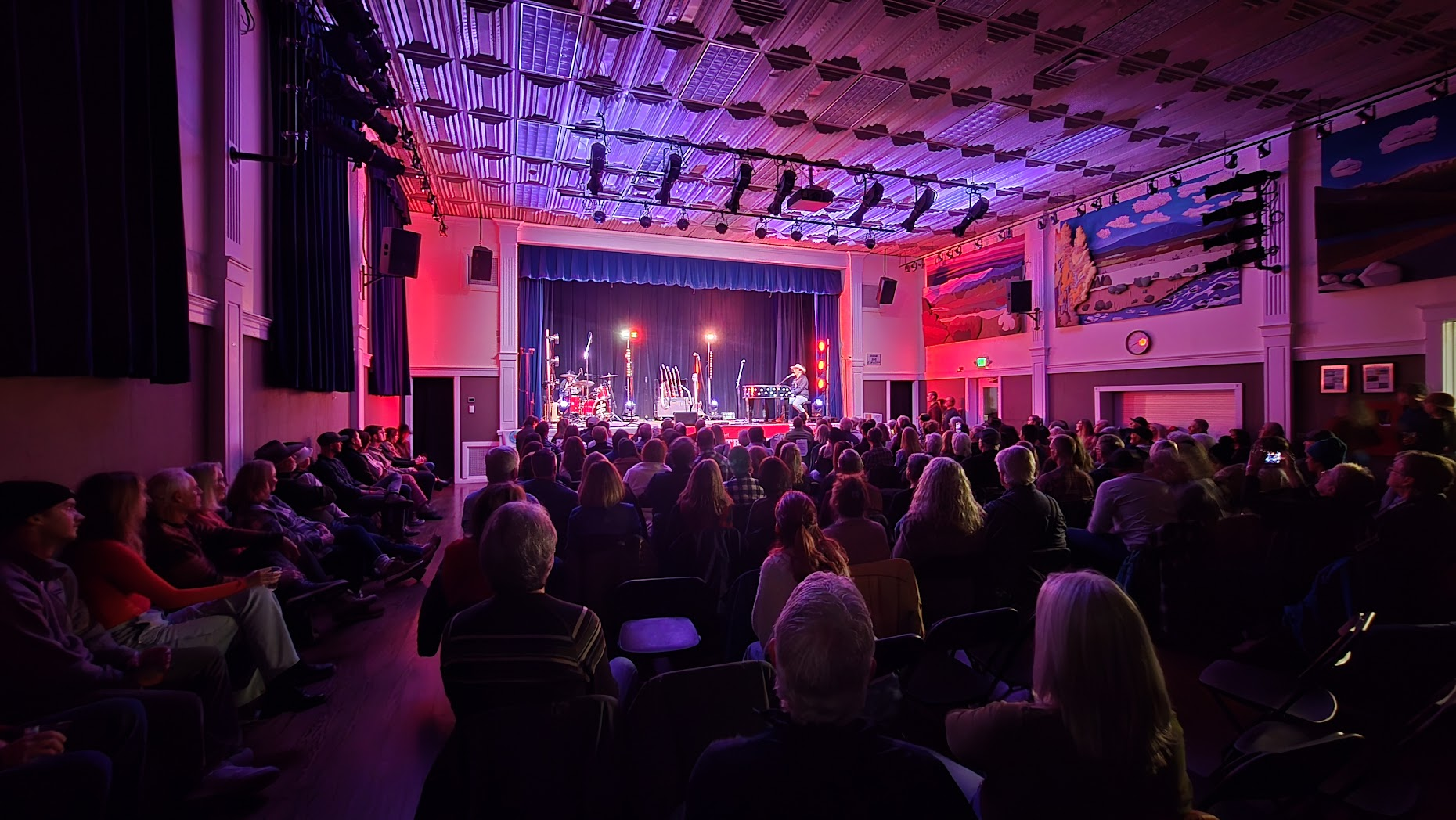 Packed auditorium at Community Arts Center concert with stage lights