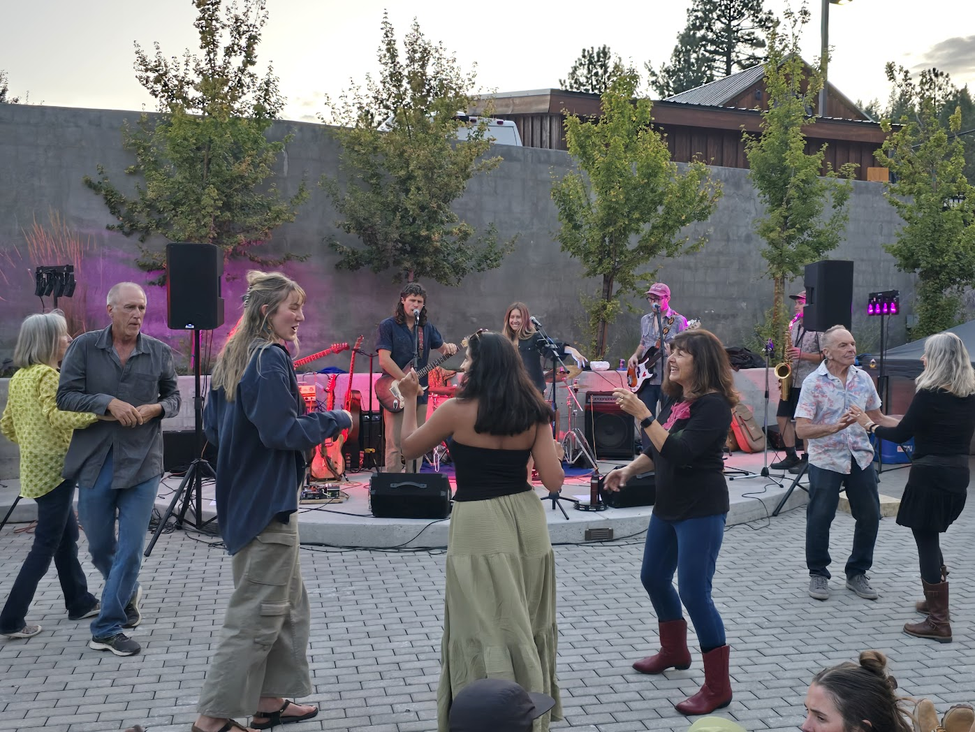 Community members dancing to live band at outdoor concert at sunset