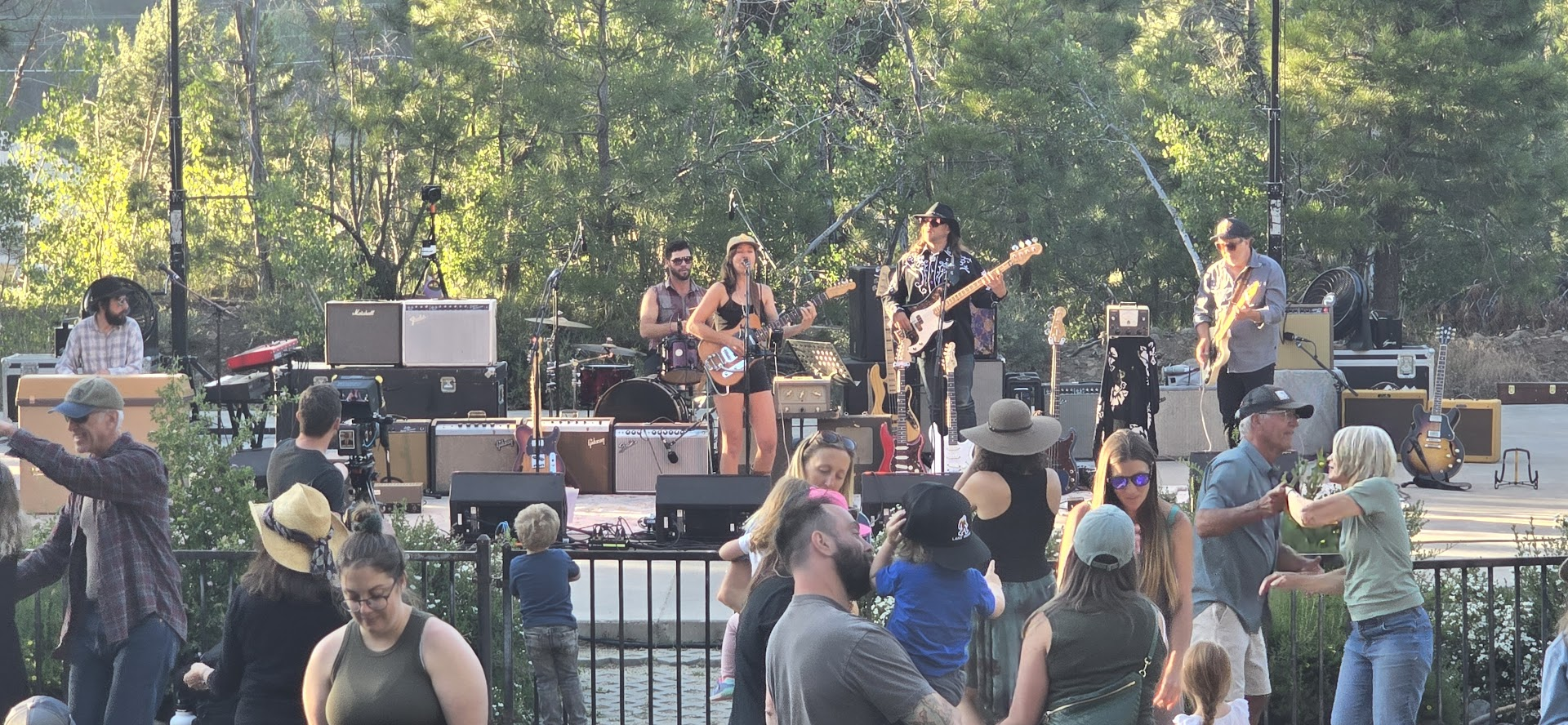 Band performing on outdoor stage with crowd dancing at Women in Music event