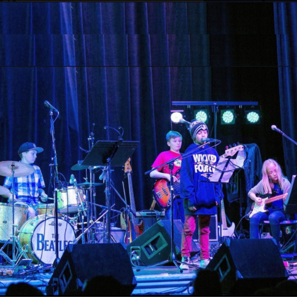Youth rock band friends performing together on stage